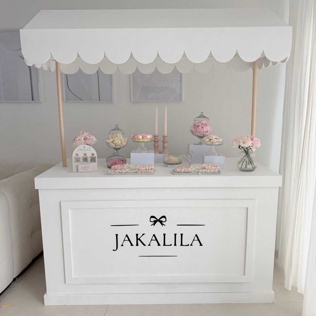 Stand de candy bar blanc avec bonbons, fleurs et décoration pastel à Thionville